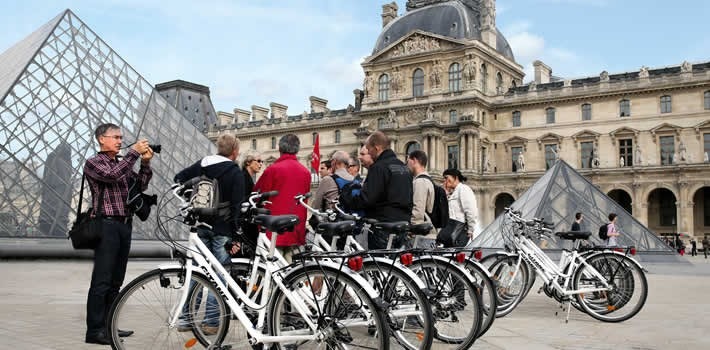 This is a picture of a group of people behind bikes at the Louvres, Paris.