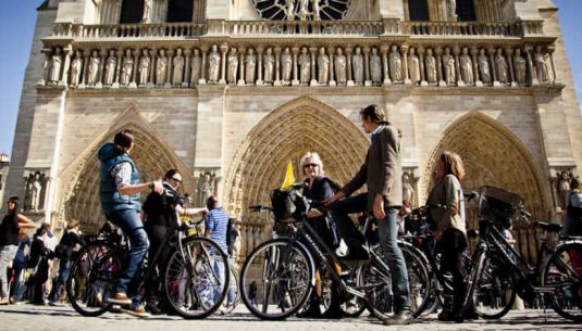 This is a picture of 6 people biking in front of Notre Dame in Paris