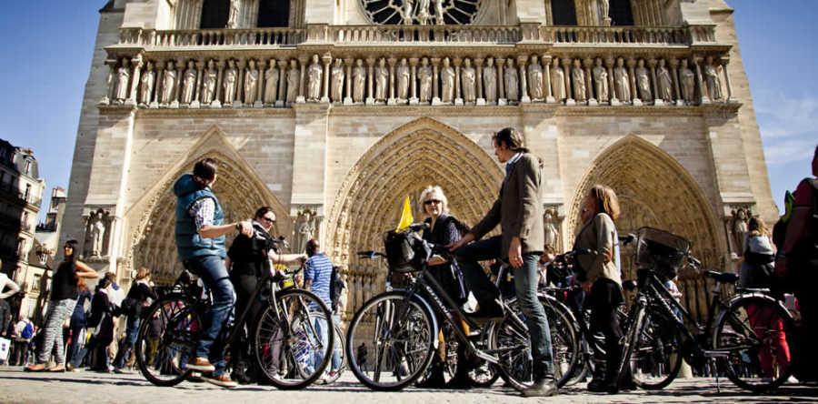 This is a picture of 6 people biking in front of Notre Dame in Paris